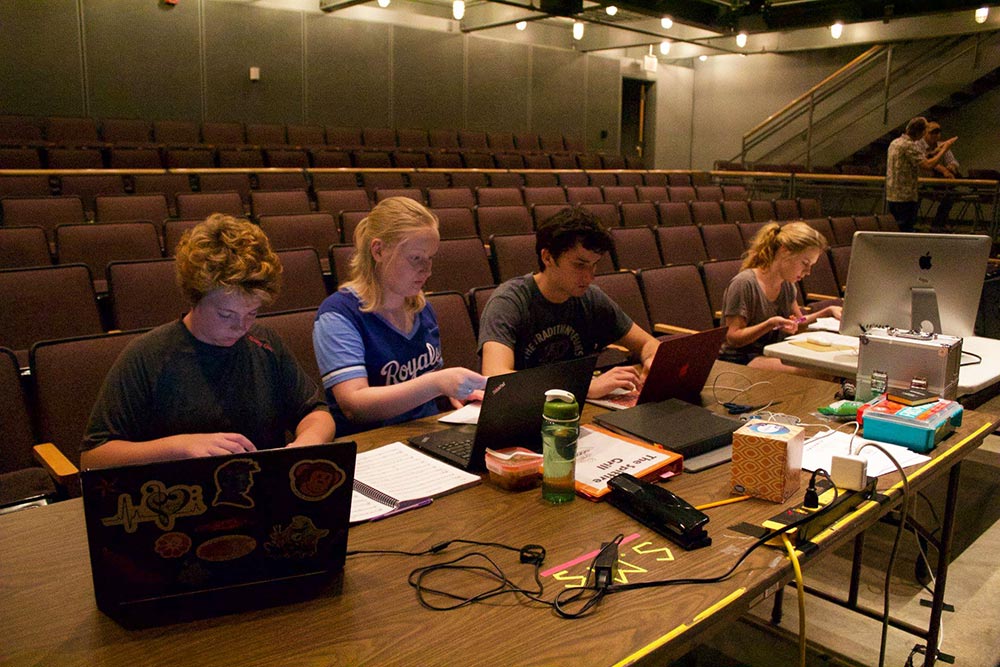 Four students at a table working on laptops