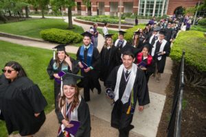 Graduates in cap and gown on their way to Commencement ceremony